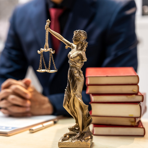 Lady justice and law books on desk.
